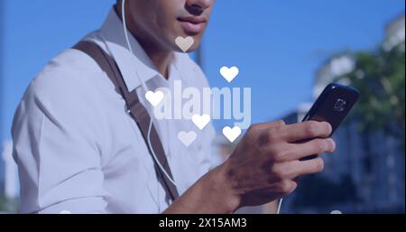 Image of social media reaction over hands of caucasian man using smartphone Stock Photo