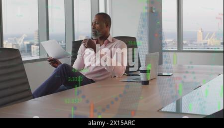 Financial data processing against african american senior businessman reading a document at office Stock Photo