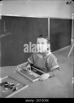 DAY NURSERY AT TOTTENHAM, LONDON, ENGLAND, 1940 - A nurse weighs a ...