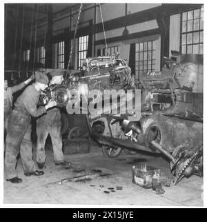 THE ACTIVITIES OF THE ROYAL ELECTRICAL AND MECHANICAL ENGINEERS - Putting engine into a Valentine tank. Left : Craftsman J. Fisher of Manchester. Right : Sgt. Darragh of Belfast. Both were fitters as civilians British Army Stock Photo