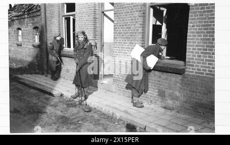 THE BRITISH ARMY IN NORTH-WEST EUROPE, 1944-1945 - Two soldiers of the 20th Field Company RE looking inside a house for booby traps, while another with a No 3 Polish Mine Detector testing the roadway for mines. The village of Meijel in Holland was found heavily mined and booby trapped. The pictures show the No 3 Polish Mine Detector, prodders and a new method of compressed air used to detect mines.The compressed air method, stated to be introduced by Lieutenant W. Campbell, of the 20th Field Company, Royal Engineers, 227th Brigade, 15th Scots Division, was in use for the first time and during Stock Photo