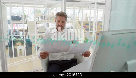 A happy business creative is working in a modern office, checking documents Stock Photo