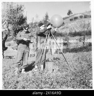 FIFTH ARMY : SPOTTING THE ENEMY GUNS - A knowledge of the wind speed and direction at various heights is necessary for accurate sound ranging. This is ascertained by the attached RAF Met. Unit, using a theodolite and a balloon filled with hydrogen. At intervals, the readings are called out by LAC S. Tyrer (right) of Stockton-on-Tees, to LAC M.G. May of London, S.W.19, who, with the aid of a slide rule, computes the winds at various heights British Army Stock Photo