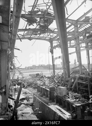 THE NAVY TAKES OVER AT KIEL. 6 TO 12 MAY 1945, THE GERMAN NAVAL BASE AT KIEL AFTER THE ROYAL NAVY HAD TAKEN IT OVER. - The capsized ADMIRAL SCHEER seen from a U-boat factory destroyed by RAF Bombing Stock Photo