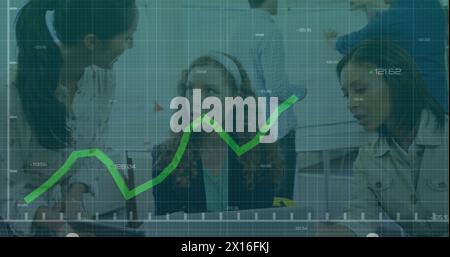Image of graph with changing numbers over diverse female coworkers discussing in office Stock Photo