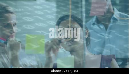 Image of binary coding over diverse business people taking notes Stock Photo