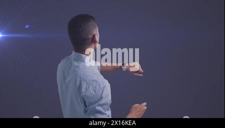 Image of caucasian businessman using smartwatch over glowing light on blue background Stock Photo