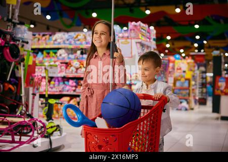 Overjoyed little sister and brother doing shopping in toys shop Stock Photo