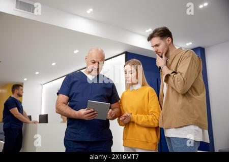 Man doctor discussing test result talking to young family couple patient Stock Photo