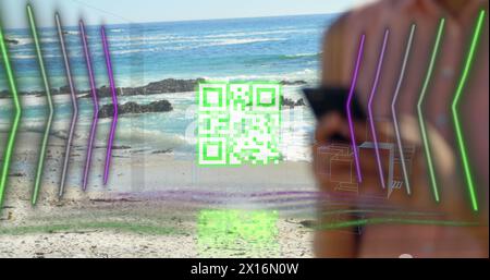 Image of qr code, digital lines with skyscrapers over caucasian woman using phone at beach Stock Photo
