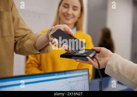 Young couple paying for doctor appointment at clinic reception using smartphone Stock Photo