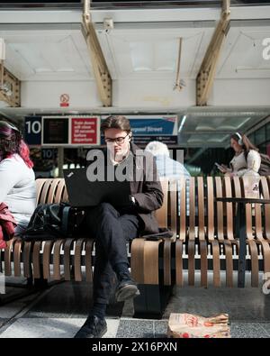 A man remote working in a train waiting room Stock Photo