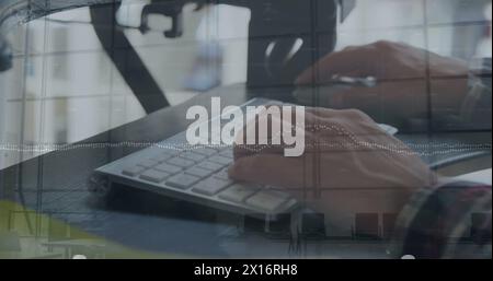 The hands of a young caucasian male business creative are shown typing on a computer keyboard and mo Stock Photo