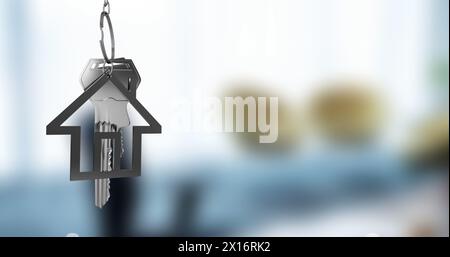 Image of silver house key fob and key dangling over out of focus interiors with copy space Stock Photo