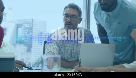 Two colleagues are talking and using a laptop in a modern office Stock Photo