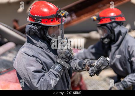 Two men in protective gear are standing next to each other. One of them is holding a radio during a rescue operation Stock Photo