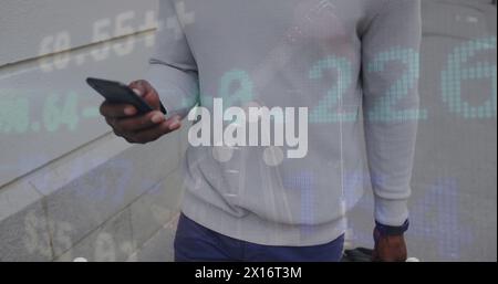 An african american man is out and about in the city, walking down the street and using his smartpho Stock Photo