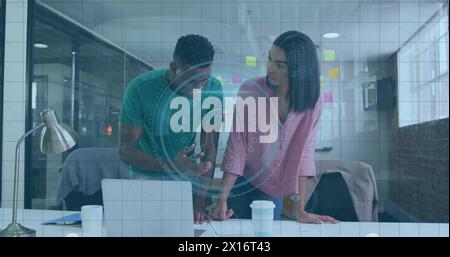 Image of fingerprint scanner over diverse male and female colleagues discussing over a plan Stock Photo