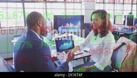 Diverse team of colleagues examining business graphs on screens Stock Photo