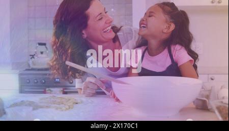 Image of lights over happy caucasisan mother and daughter cooking together Stock Photo
