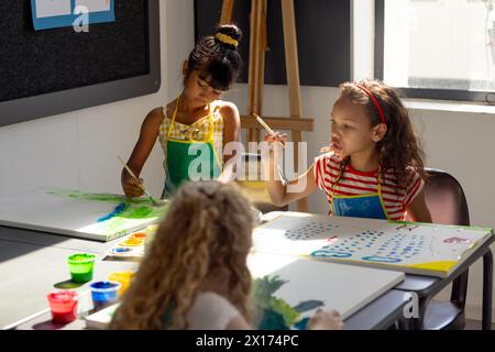 In school, during art class, diverse young students painting on canvas Stock Photo