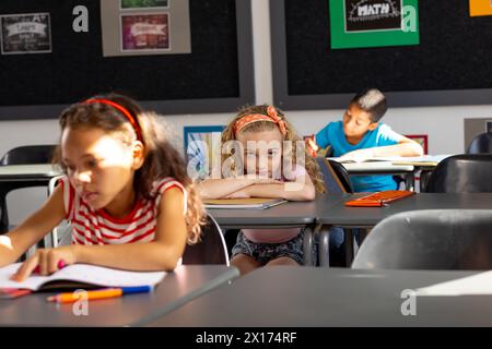 In school, diverse group of young students focusing on their tasks in the classroom Stock Photo