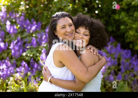 Mother and Daughter, mature biracial woman and young biracial woman hugging in garden at home Stock Photo