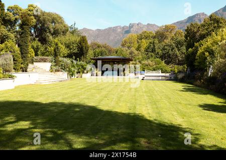 Lush green lawn stretches in front of large house with mountains behind ...