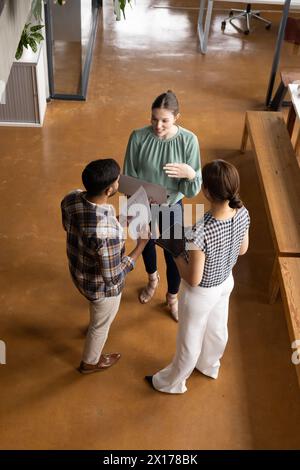 Diverse colleagues are discussing papers in a modern business office hallway Stock Photo