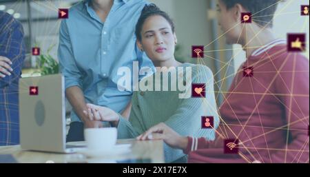 Image of globes of digital icons over group of diverse colleagues discussing together at office Stock Photo