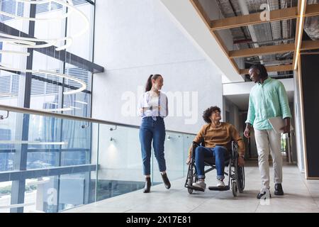 Diverse group of friends walking and talking in modern hallway in a modern business office Stock Photo