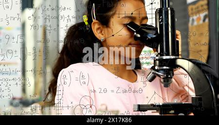 Image of mathematical formulae over smiling schoolgirl using microscope Stock Photo