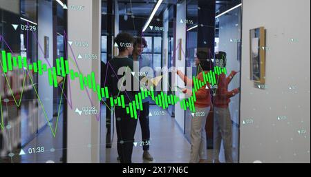 Image of graphs and changing numbers, diverse coworkers discussing in corridor of office Stock Photo