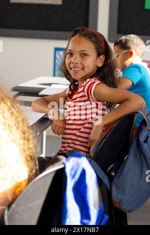 In school, young biracial girl and two friends are sitting in the classroom Stock Photo