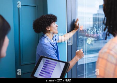 A diverse group of young adults is brainstorming with sticky notes in a modern business office Stock Photo