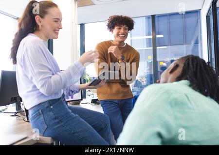 Diverse team discussing over tablet in a modern business office, African American man listening Stock Photo