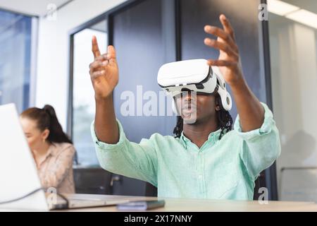 African American man wearing virtual reality headset, gesturing in a modern business office Stock Photo