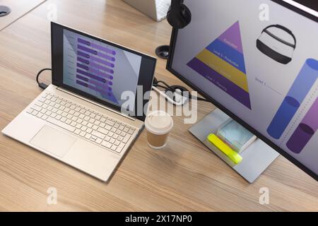 Laptop and monitor displaying colorful VR graphs on wooden desk in a modern business office Stock Photo