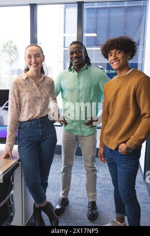 Diverse group of colleagues standing together, smiling, in a modern business office Stock Photo