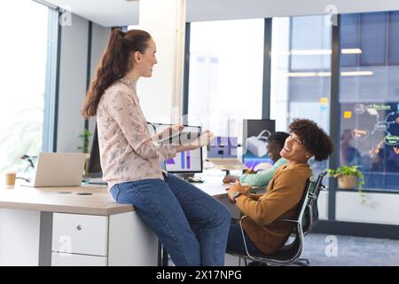 Diverse team discussing in office, Caucasian woman holding tablet Stock Photo