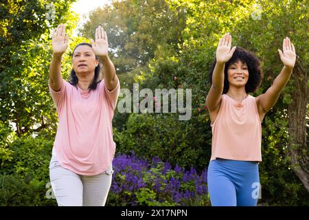 Mature biracial woman and young biracial woman practicing yoga outdoors, at home Stock Photo
