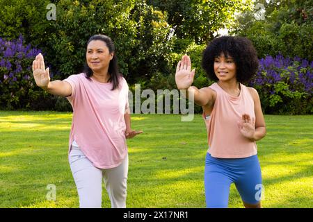 Mature biracial woman and young biracial woman practicing tai chi in park Stock Photo