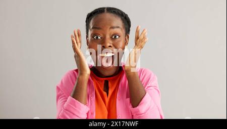 Excited, black woman and surprise with good news for winning, celebration or prize on a gray studio background. Portrait of African female person with Stock Photo