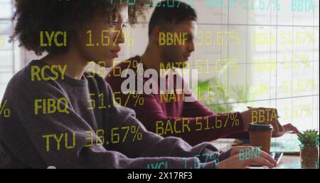 Image of trading board over multiracial coworkers working on laptops at office Stock Photo