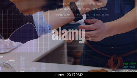 Image of trading board and graph over cropped hand of man scanning smartwatch for paying in cafe Stock Photo