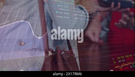 Image of trading board, graphs over midsection of woman inserting password on credit card reader Stock Photo