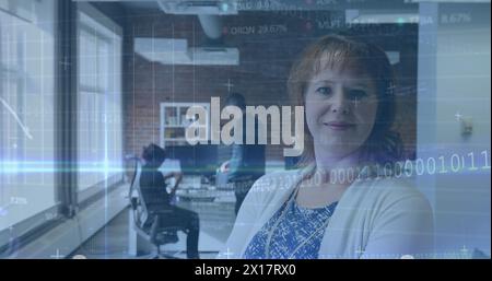 Image of binary codes, computer language, trading board over caucasian woman standing in office Stock Photo