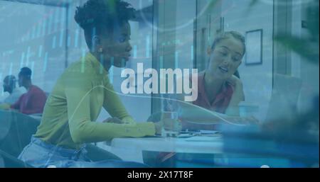 Image of financial data processing over diverse female colleagues discussing work in office Stock Photo