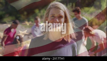Composite image of american flag over portrait of caucasian female volunteer smiling in the forest Stock Photo