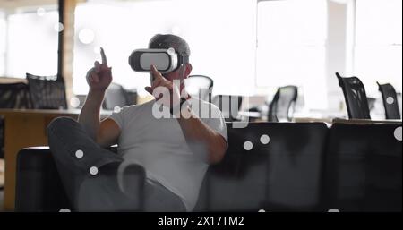 Image of spots over caucasian businessman using vr headset in office Stock Photo